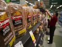 Loaves of Canada Bread Co. Ltd. Dempster's multigrain bread are displayed for sale as an employee stocks shelves at a grocery store in Vancouver. 
