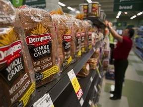 Loaves of Canada Bread Co. Ltd. Dempster's multigrain bread are displayed for sale as an employee stocks shelves at a grocery store in Vancouver.