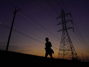 FILE - A jogger passes power lines during a sunset run, Aug. 20, 2023, in San Antonio, as high temperatures continue to stress the power grid. On Thursday, Sept. 7, Texas' power grid manager again asked residents to cut back on electricity as a prolonged and punishing summer heat wave continued, a day after the system was pushed to brink of outages for the first time since a deadly winter blackout in 2021.