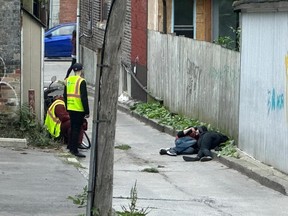 Security staff look on as two drug users lay on the curb.