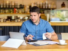 Entrepreneur using laptop and calculator to work and to calculate and analyze financial expenses of new business start-up