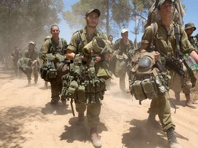 Israeli soldiers walk to their deployment area near Israel's border with the Gaza Strip on July 18, 2014