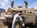 An Israeli sodleir prays standing in front of a Merkava tank on the outskirts of the northern town of Kiryat Shmona near the border with Lebanon on October 8, 2023.