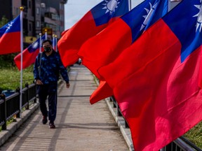 A man walks past the Taiwan's national flags on Nangan Island in Taiwan's Matsu Archipelago on Oct. 13, 2023.