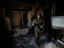 An Israeli soldier inspects a house damaged by Hamas militants in Kibbutz Be'eri, Israel, Tuesday, Oct. 17, 2023.