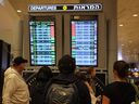 Passengers look at a departure board at Ben Gurion Airport near Tel Aviv, Israel, on Oct. 7, 2023, as flights are cancelled because of the Hamas attacks. The conflict sparked major disruption at Tel Aviv airport, with many carriers cancelling flights.