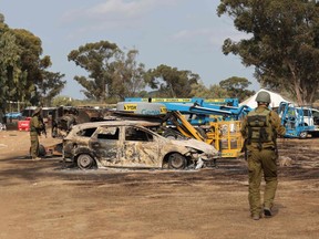 Israeli troops inspect the ravaged site of the attack on the Supernova desert music Festiva