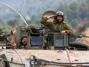 Smiling Israeli soldiers in an armoured vehicle.