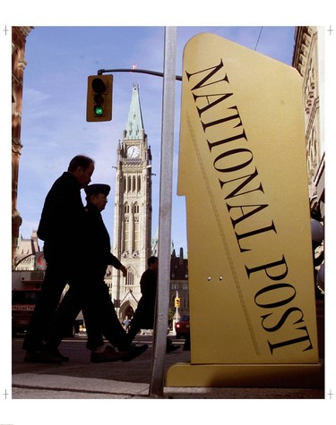 Pedestrians walk by a National Post newspaper box in Ottawa.