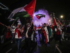 People wave Palestinian flags as smoke bombs are set off during a demonstration in support of Palestine following the brutal Hamas attack on Israel, in Vancouver on Oct. 19, 2023.