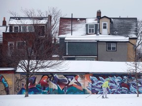 A man cross country skis past houses on the edge of Trinity Bellwoods Park in Toronto, Ontario as a mix of snow, hail, and rain fall on Sunday, April 15. 2018.