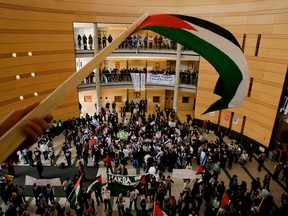 A man waves a Palestinian flag while pro-Israel and pro-Palestine supporters divide York University's Vari Hall.