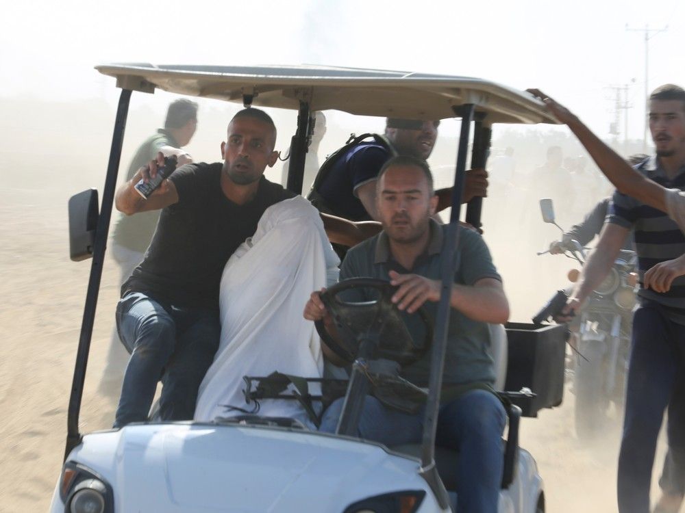 Palestinians transport a captured Israeli civilian from Kfar Azza kibbutz into the Gaza Strip on Saturday, Oct. 7, 2023. Palestinians transport a captured Israeli civilian from Kfar Azza kibbutz into the Gaza Strip on Saturday, Oct. 7, 2023.