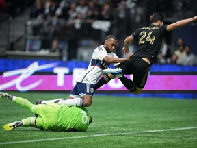 Los Angeles FC goalkeeper Maxime Crepeau, bottom left, makes the save as Vancouver Whitecaps' Junior Hoilett, centre, and Los Angeles' Ryan Hollingshead (24) tumble over him during the second half of an MLS soccer match, in Vancouver, B.C., Saturday, Oct. 21, 2023.