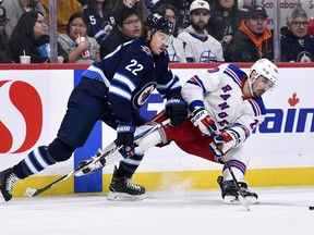 New York Rangers' Chris Kreider (20) passes the puck as he is checked by Winnipeg Jets' Mason Appleton (22) during second period NHL action in Winnipeg on Monday October 30, 2023.