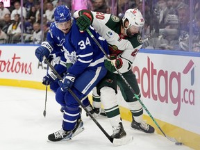 Toronto Maple Leafs centre Auston Matthews (34) and Minnesota Wild left wing Pat Maroon (20) vie for control of the puck during first period NHL hockey action, in Toronto, Saturday, Oct. 14, 2023.