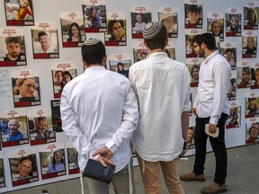 Israeli men look at photos of Israelis missing and held hostage in Gaza.