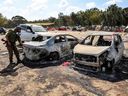 An Israeli army soldier searches torched vehicles at the site of the October 7 attack by Hamas terrorists on a music festival near Kibbutz Reim in southern Israel. The initial attack by Hamas and Israel's response in Gaza have left many hundreds of civilians dead, including children.