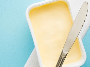 Opened plastic pack of light yellow margarine and knife