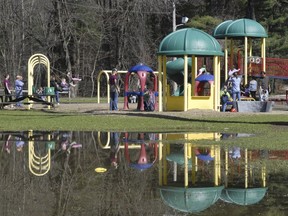 FILE - A playground at Bliss Park is reflected in standing water in this April 2, 2010, file photo in Longmeadow, Mass. Two juveniles have been arrested for allegedly dousing playground equipment in Massachusetts with acid in an incident this summer that injured four children, the Hamden District Attorney Anthony Gulluni said.