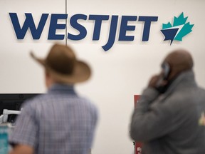 Passengers wait in line at the WestJet counter at Calgary International Airport.