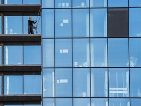 A construction worker checks his safety gear while working on a balcony on a high-rise residential building under construction in Arlington, VA., Monday, Oct. 16, 2023. On Tuesday, the government is releasing its latest quarterly report on wages and salaries. In the previous report, those labor costs grew more slowly, suggesting that employers were feeling less pressure to boost pay.