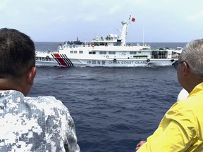 In this image made from video provided by PTV4 (People's Television News) Government Channel, Philippine special envoy to China Teodoro Locsin Jr., right, looks at a Chinese Coast Guard ship near the Second Thomas Shoal on Oct. 4, 2023, while onboard a Philippine coast guard vessel that escorted two Philippine boats to deliver food and other supplies to a Filipino marine territorial outpost in the Second Thomas Shoal.