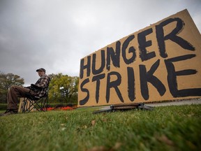 Michael Sorowski who is staging a hunger strike after a surgery let him unable to work, sits outside the Saskatchewan Legislative Building on Monday, October 2, 2023 in Regina.