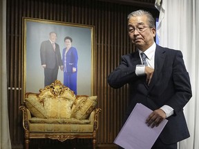 Nobuo Okamura, the legal affairs department chief for the Unification Church, walks past a portrait of its founder Sun Myung Moon, left, and his wife Hak Ja Han, as he leaves a news conference at the church's Japan headquarters in Tokyo, Monday, Oct. 16, 2023. The Japanese branch of the Unification Church on Monday criticized the Japanese government's request for a court order to dissolve the group, saying it's based on groundless accusations and is a serious threat to religious freedom and human rights of its followers.