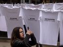 A woman takes a photograph of shirts at Toronto’s David Pecaut Square at an installation called “Threads of Hope” with the names of those taken hostage by Hamas terrorists from Israel to Gaza, Wednesday November 22, 2023.