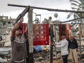 Palestinian men set up a structure amid the destruction caused by Israeli strikes in the village of Khuzaa, near the border fence between Israel and the southern Gaza Strip on Monday,
