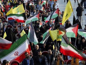 People wave Palestinian, Iranian and Hezbollah flags as they gather in the Imam Hussein square in Tehran, during the televised speech of Lebanese Hezbollah chief Hassan Nasrallah Nov. 3, 2023. Nasrallah told the United States on Nov. 3, that his Iran-backed group was ready to face its warships and the way to prevent a regional war was to halt the attacks in Gaza.