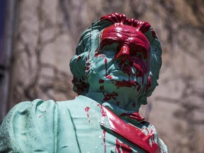 A statue of Egerton Ryerson splashed with red paint.