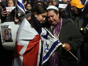 A mother and daughter embrace as members of the Jewish community hold a vigil for the more than 200 Israelis, including 30 children, held hostage by Hamas, on Parliament Hill in Ottawa on Oct. 28, 2023.