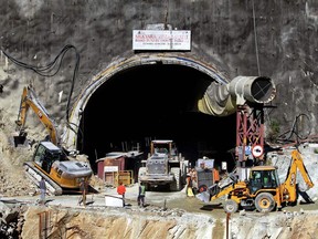 Rescue workers stand at an entrance of the under construction road tunnel