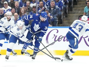 Toronto Maple Leafs centre Auston Matthews (34) battles Tampa Bay Lightning center Brayden Point (21) and Lightning defenceman Darren Raddysh (43) for control of the puck during second period NHL hockey action in Toronto on Monday November 6, 2023.THE CANADIAN PRESS/Chris Young