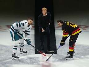 Prince Harry, Duke of Sussex, drops the puck for San Jose Sharks' Tomas Hertl, left, and Vancouver Canucks' Quinn Hughes during a ceremonial faceoff before a game at Rogers Arena on Monday night