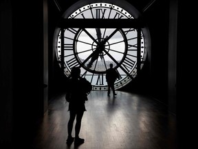 People walk by a giant clock