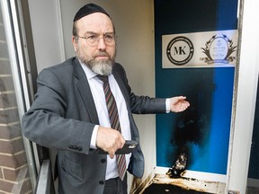 A member of the Jewish community examines the damage after an incendiary object was allegedly thrown against the door of a Jewish community centre on Nov. 27, 2023.