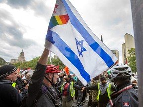 A man holds an Israeli flag at a Pro-Palestinian march in front of Nathan Phillips Square in downtown Toronto on Oct. 9, 2023.