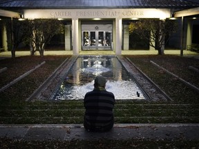 Royce Soble, of Atlanta, sits near a reflection pool at The Carter Center after former first lady Rosalynn Carter has died, Sunday, Nov. 19, 2023, in Atlanta. "I just wanted to sit here and share a moment of peace and say my respects for the family," Soble said.