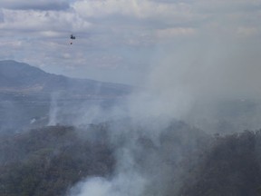This photo provided by the Hawaii Department of Land and Natural Resources shows an Army helicopter carrying water to douse a wildfire burning east of Mililani, Hawaii, on Thursday, Nov. 2, 2023. A wildfire that has burned forestlands in a remote mountainous area of Central Oahu has moved eastward and away from population centers as firefighters continued to battle the blaze.