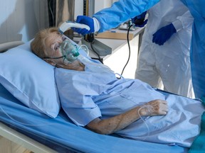 An elderly woman lying on a hospital bed.