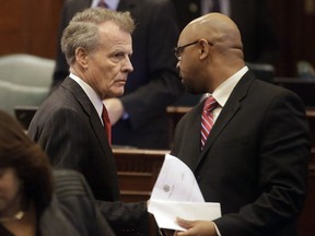 FILE -Illinois Speaker of the House Michael Madigan, D-Chicago, left, speaks with Illinois Rep. Thaddeus Jones, D-Calumet, right, while on the House floor after adjoining veto session, Thursday, Nov. 7, 2013 in Springfield Ill. Officials in a suburban Chicago community have issued municipal citations to a local news reporter for what they say are persistent contacts with city officials for comment on treacherous fall flooding.
