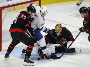 Tampa Bay Lightning's Brayden Point (21) battles for the puck with Ottawa Senators' Rourke Chartier (49), Jakob Chychrun (6), and goaltender Joonas Korpisalo (70) during second period NHL hockey action at the Canadian Tire Centre in Ottawa on Saturday, Nov. 4, 2023.