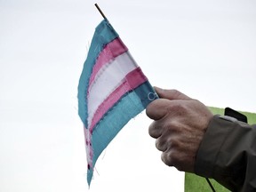 FILE - A person holds a transgender flag to show their support for the transgender community during the sixth annual Transgender Day of Remembrance at Maryville College, Nov. 20, 2016, in Maryville, Tenn. According to court documents filed Wednesday, Nov. 1, 2023, the American Civil Liberties Union and attorneys representing Tennessee transgender teens and their families have asked the U.S. Supreme Court to block a ban on gender-affirming care for minors that a lower court allowed to go into effect.