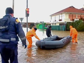 In this photo taken from video released by Russian Emergency Ministry Press Service, Russian Emergency Ministry rescuers arrive to evacuate people after storm and flooding near Evpatoria in Crimea, Monday, Nov. 27, 2023. A storm in the Black Sea took down power grids and left almost half a million people without power after it flooded roads, ripped up trees and damaged buildings in Crimea, Russian state news agency Tass said. (Russian Emergency Ministry Press Service via AP)
