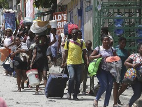 FILE - Residents flee their homes to escape clashes between armed gangs in the Carrefour-Feuilles district of Port-au-Prince, Haiti, Aug. 15, 2023. Kenya's government said Nov. 9, 2023 that its police will not be deployed to Haiti until all conditions on training and funding are met in line with last month's approval from the U.N Security Council to give the eastern African country command of a multinational mission to combat violent gangs in Haiti.