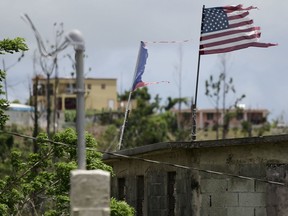 FILE - Deteriorated U.S. and Puerto Rico flags fly on a roof eight months after the passing of Hurricane Maria in the Barrio Jacana Piedra Blanca area of Yabucoa, a town where many continue without power in Puerto Rico, May 16, 2018. A federal judge on Tuesday, Nov. 14, 2023, tentatively approved a portion of the newest plan to restructure $10 billion of debt owed by Puerto Rico's power company amid heated negotiations between creditors and the U.S. territory's government.