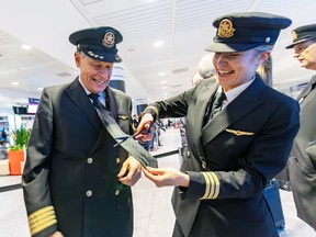 Retiring Air Canada pilot Jean Castonguay has his tie cut off, as per tradition, by his daughter, First Officer Marie-Pierre, after his last flight from Toulouse, at Trudeau airport in Montreal on Monday, Dec. 11, 2023.